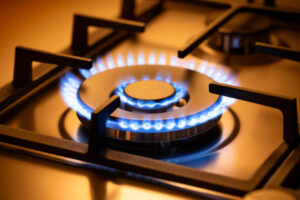 Range burner of a natural gas home stove surrounded by a blue flame.